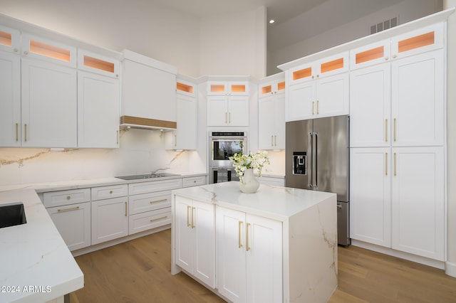 kitchen with light wood-type flooring, stainless steel appliances, light stone counters, and white cabinetry