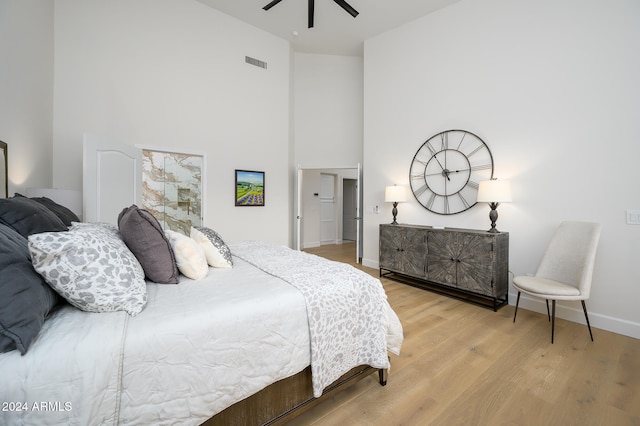 bedroom with hardwood / wood-style floors, ceiling fan, and a high ceiling