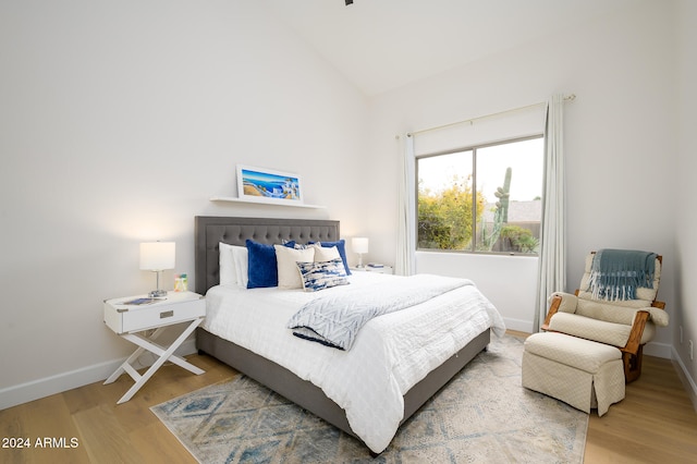 bedroom with high vaulted ceiling and wood-type flooring