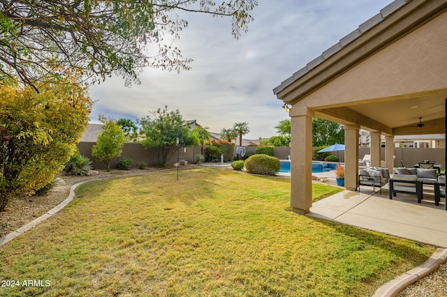 view of yard featuring outdoor lounge area, a patio, a fenced in pool, and ceiling fan