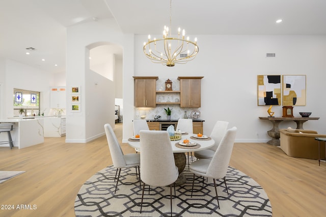 dining area featuring a notable chandelier, vaulted ceiling, and light wood-type flooring