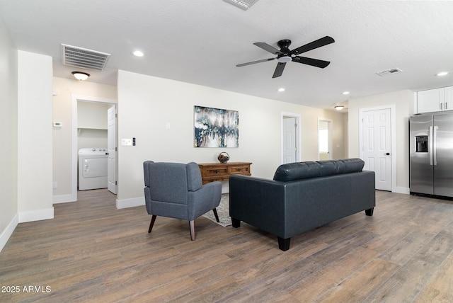 living room featuring dark hardwood / wood-style floors, ceiling fan, washer / dryer, and a textured ceiling