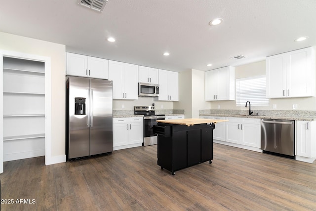 kitchen featuring stainless steel appliances, dark wood-type flooring, sink, white cabinets, and a kitchen island