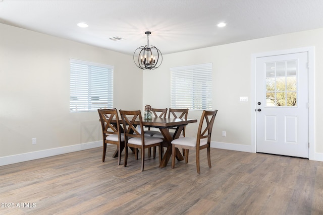 dining area with hardwood / wood-style floors and an inviting chandelier