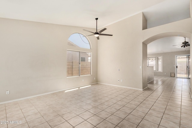 6317 E Colby St, Mesa, AZ 85205 - empty room featuring a ceiling fan, light tile patterned floors, arched walkways, baseboards, and a high ceiling