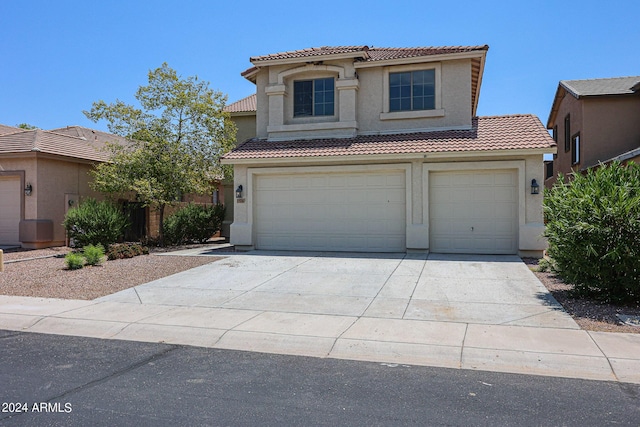 mediterranean / spanish-style house featuring driveway, an attached garage, a tile roof, and stucco siding