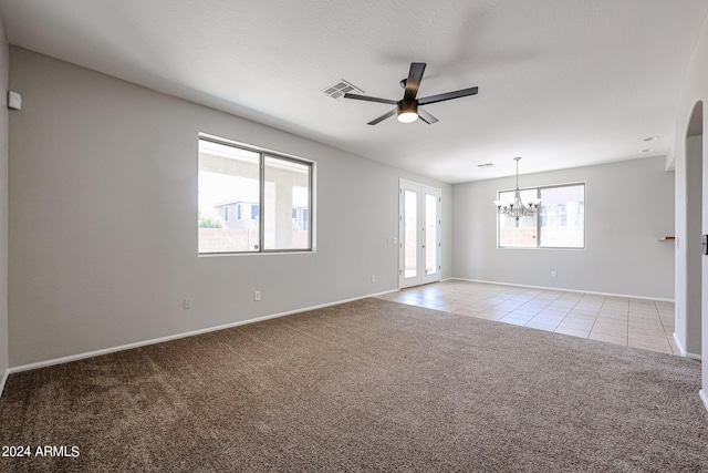 empty room with light carpet, light tile patterned floors, baseboards, visible vents, and ceiling fan with notable chandelier