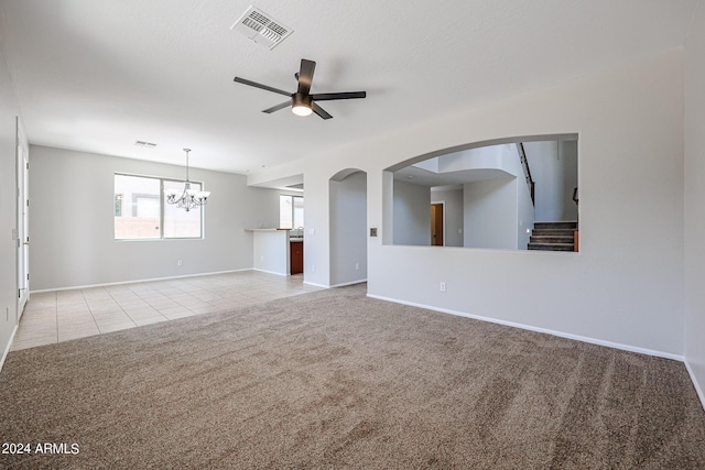 unfurnished living room with tile patterned flooring, ceiling fan with notable chandelier, carpet floors, visible vents, and baseboards