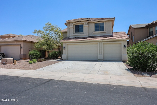 view of front of property with concrete driveway, an attached garage, a tiled roof, and stucco siding