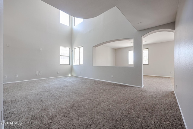 empty room featuring carpet, arched walkways, and baseboards