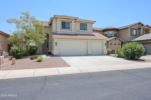 mediterranean / spanish-style home featuring driveway, an attached garage, a tiled roof, and stucco siding