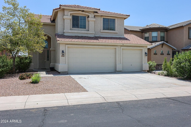 view of front facade with a garage, driveway, a tile roof, and stucco siding