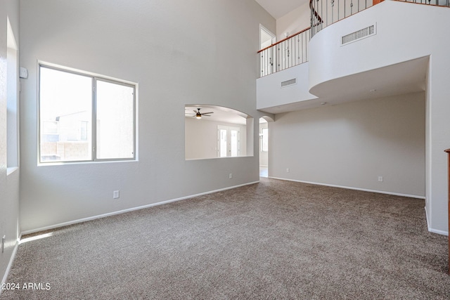 unfurnished living room featuring arched walkways, visible vents, and carpet