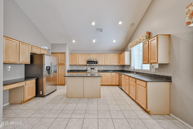 kitchen with stainless steel appliances, light brown cabinets, dark countertops, high vaulted ceiling, and a center island