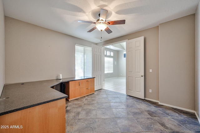 empty room featuring ceiling fan and baseboards
