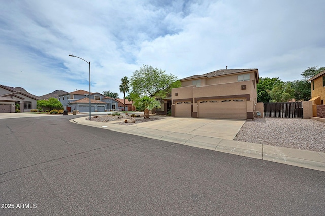 view of front of house featuring driveway, fence, stucco siding, a residential view, and an attached garage