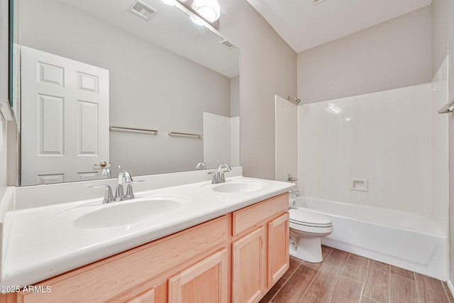 bathroom featuring toilet, shower / washtub combination, double vanity, and wood finished floors