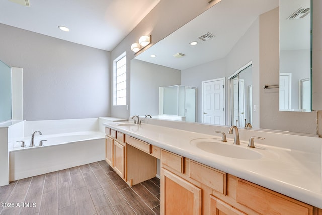 full bathroom with a bath, double vanity, wood finished floors, recessed lighting, and an enclosed shower
