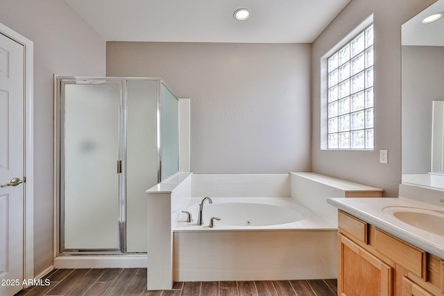 bathroom with wood finished floors, a bath, a shower stall, vanity, and recessed lighting