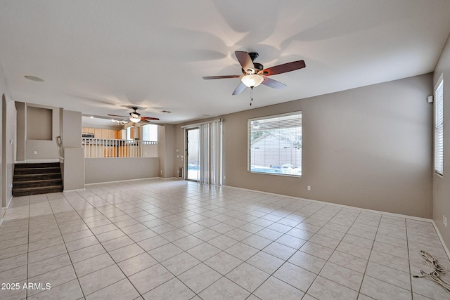 unfurnished room featuring a ceiling fan, plenty of natural light, light tile patterned floors, and stairs