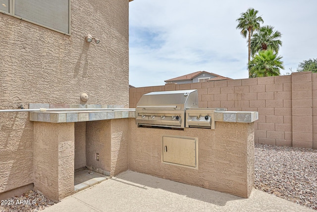 view of patio / terrace with exterior kitchen, fence, and a grill