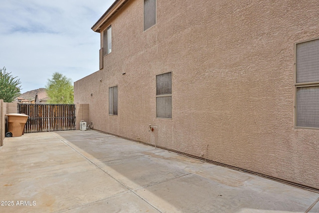 view of side of home with stucco siding, a patio, and fence