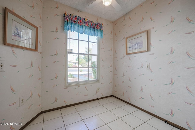 unfurnished room with ceiling fan, light tile patterned floors, and a textured ceiling