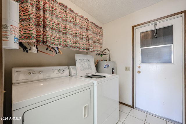 clothes washing area with washer and clothes dryer, light tile patterned floors, a textured ceiling, and water heater