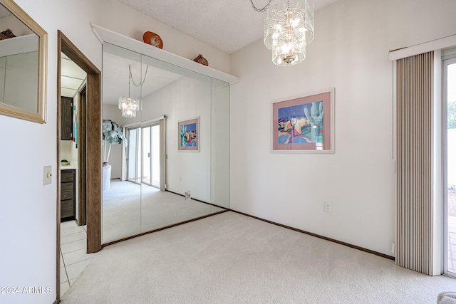 spare room with a healthy amount of sunlight, light colored carpet, and an inviting chandelier