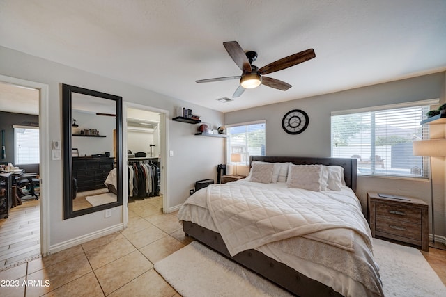 bedroom featuring light tile patterned flooring, a walk in closet, a closet, and ceiling fan