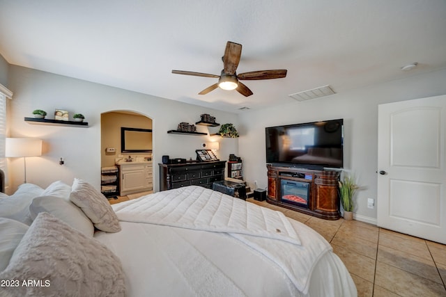 tiled bedroom featuring connected bathroom and ceiling fan