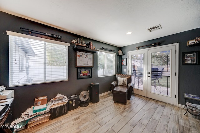 living area with light hardwood / wood-style flooring, french doors, and a wealth of natural light