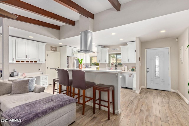 kitchen featuring stainless steel appliances, light hardwood / wood-style flooring, island range hood, and white cabinets