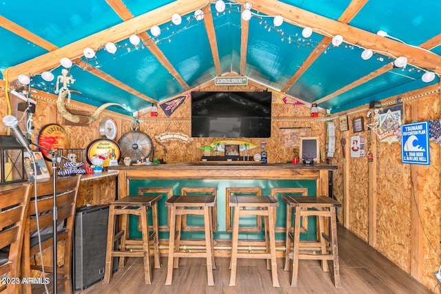 bar featuring vaulted ceiling and hardwood / wood-style flooring