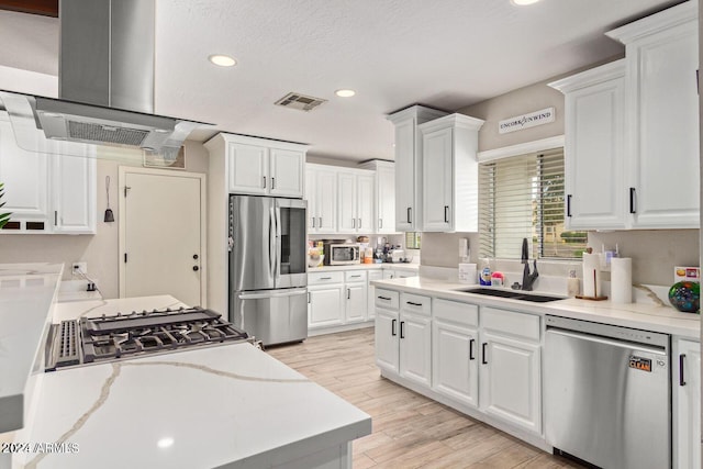 kitchen with exhaust hood, appliances with stainless steel finishes, white cabinetry, light wood-type flooring, and sink