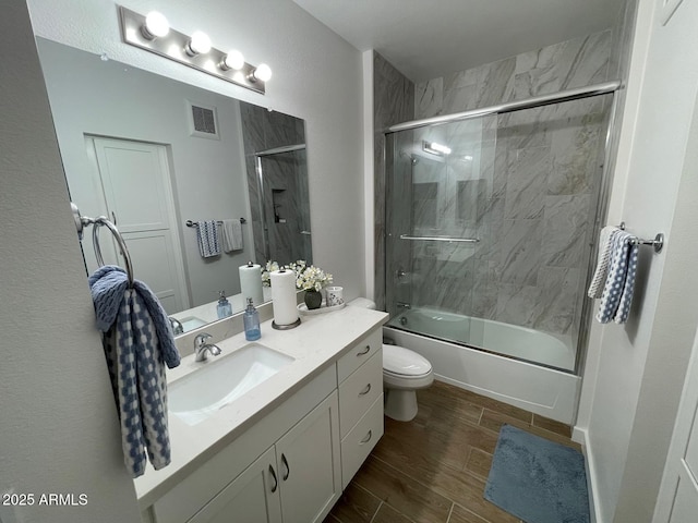 full bathroom with toilet, bath / shower combo with glass door, and vanity