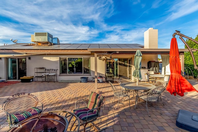 rear view of house featuring an outdoor fire pit, a patio area, solar panels, and central air condition unit