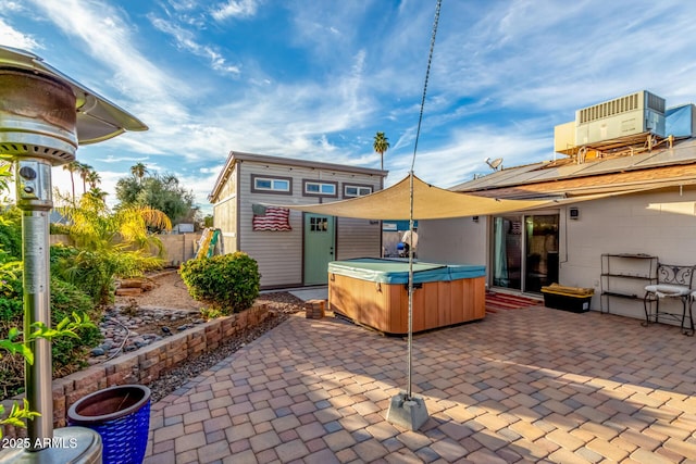 view of patio / terrace with cooling unit, an outbuilding, and a hot tub