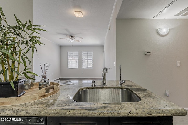 kitchen with a sink, baseboards, light stone countertops, and a ceiling fan