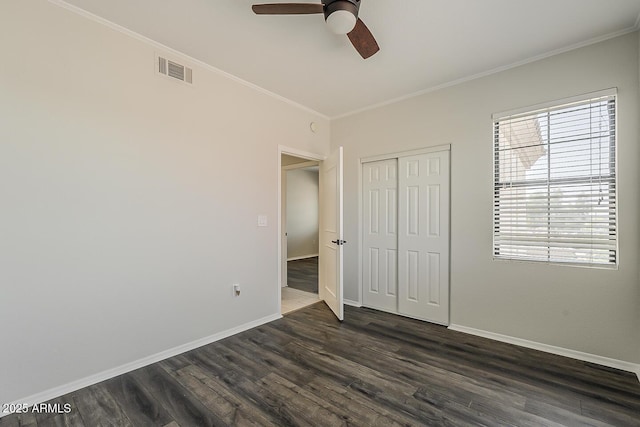 unfurnished bedroom featuring crown molding, baseboards, visible vents, and dark wood finished floors