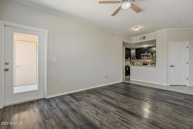 unfurnished living room with baseboards, ornamental molding, a ceiling fan, and dark wood-type flooring