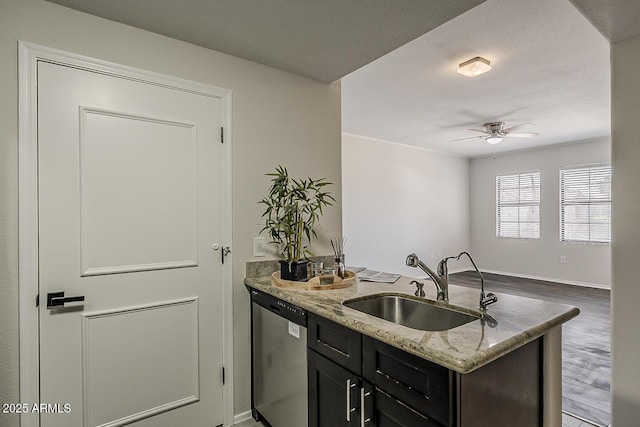 kitchen with ceiling fan, light stone counters, a sink, a peninsula, and stainless steel dishwasher