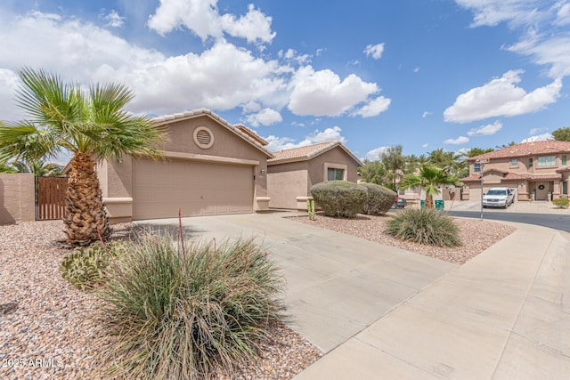 view of front of house with driveway, a gate, stucco siding, an attached garage, and a tiled roof