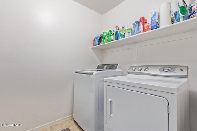 washroom with baseboards, washing machine and clothes dryer, and laundry area