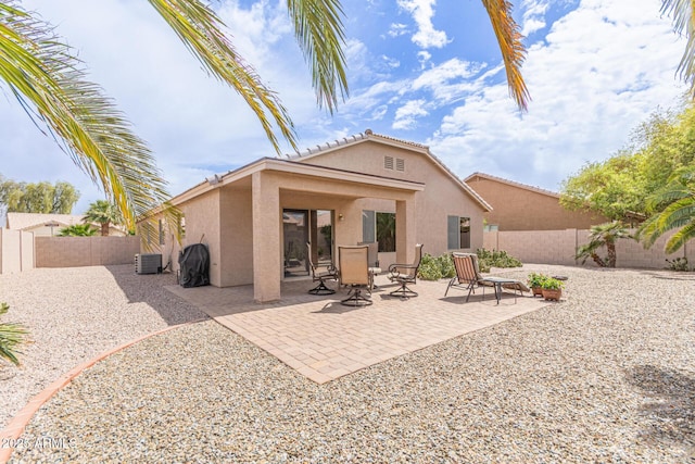 back of property with stucco siding, a fenced backyard, a patio, and central AC