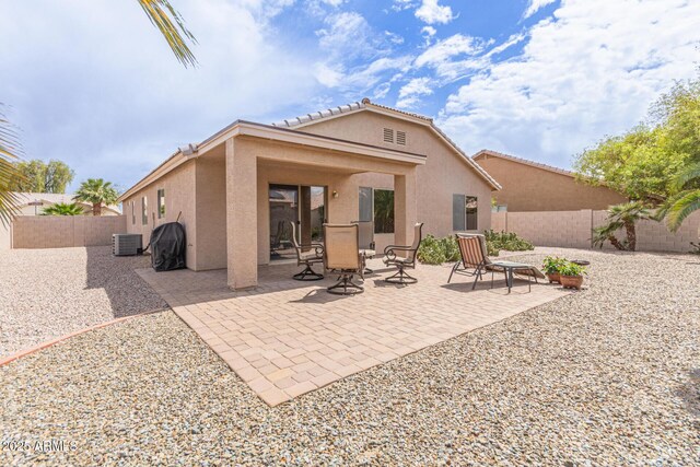 back of property with stucco siding, central air condition unit, a tiled roof, a fenced backyard, and a patio area