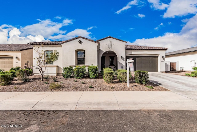 mediterranean / spanish-style house with a tiled roof, stucco siding, an attached garage, and concrete driveway