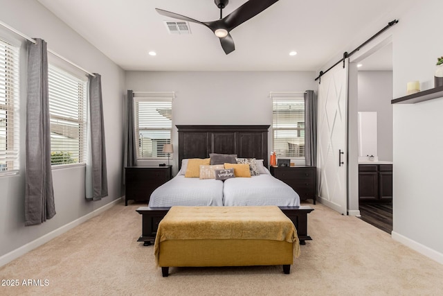 bedroom with visible vents, baseboards, a barn door, multiple windows, and light colored carpet