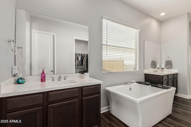 full bath with a freestanding bath, wood finished floors, baseboards, and a sink