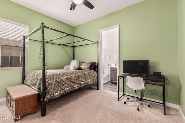 carpeted bedroom featuring ensuite bath, baseboards, and ceiling fan